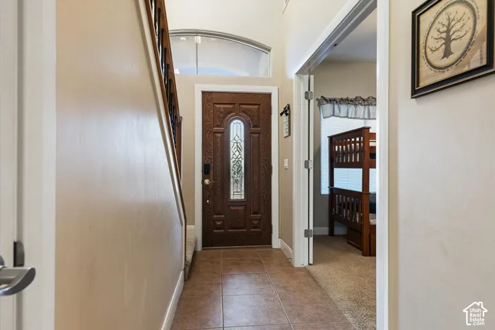 Entryway featuring a wood-panel door with decorative glass, arched transom window, and tile flooring