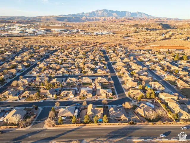 Residential development with a mountainous backdrop, featuring numerous single-story homes and a paved street network