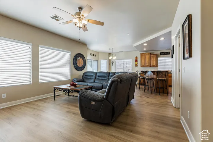 Wood-finish flooring throughout, vaulted ceiling, recessed lighting, and a ceiling fan with integrated lighting