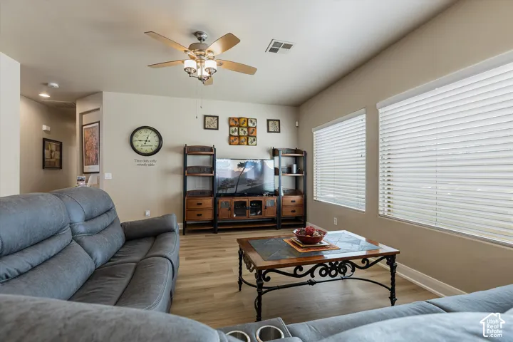 Vaulted ceiling with a ceiling fan, wood-finish flooring, and multiple windows with blinds