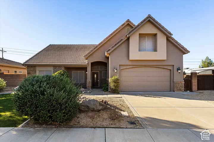 Stucco exterior with stone accents, a tile roof, an arched entry, an integrated garage, and a concrete driveway