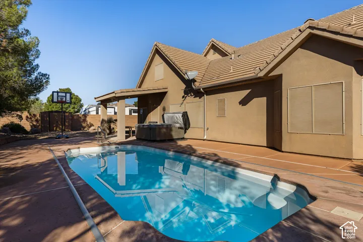 Rear exterior with a tiled roof, stucco siding, and a private swimming pool