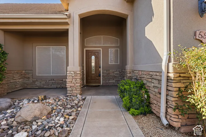 Stucco exterior with stacked stone accents, covered entry, wood-finish front door with arched transom, and concrete pathway