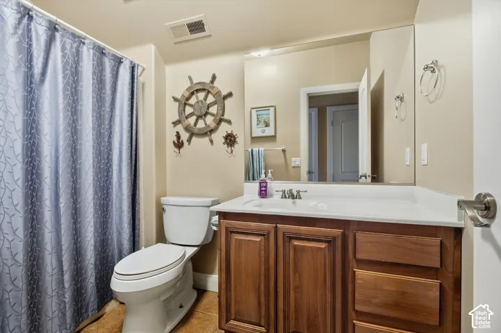 Bathroom featuring a wood-finish vanity with ample storage, a white countertop, and an integrated sink