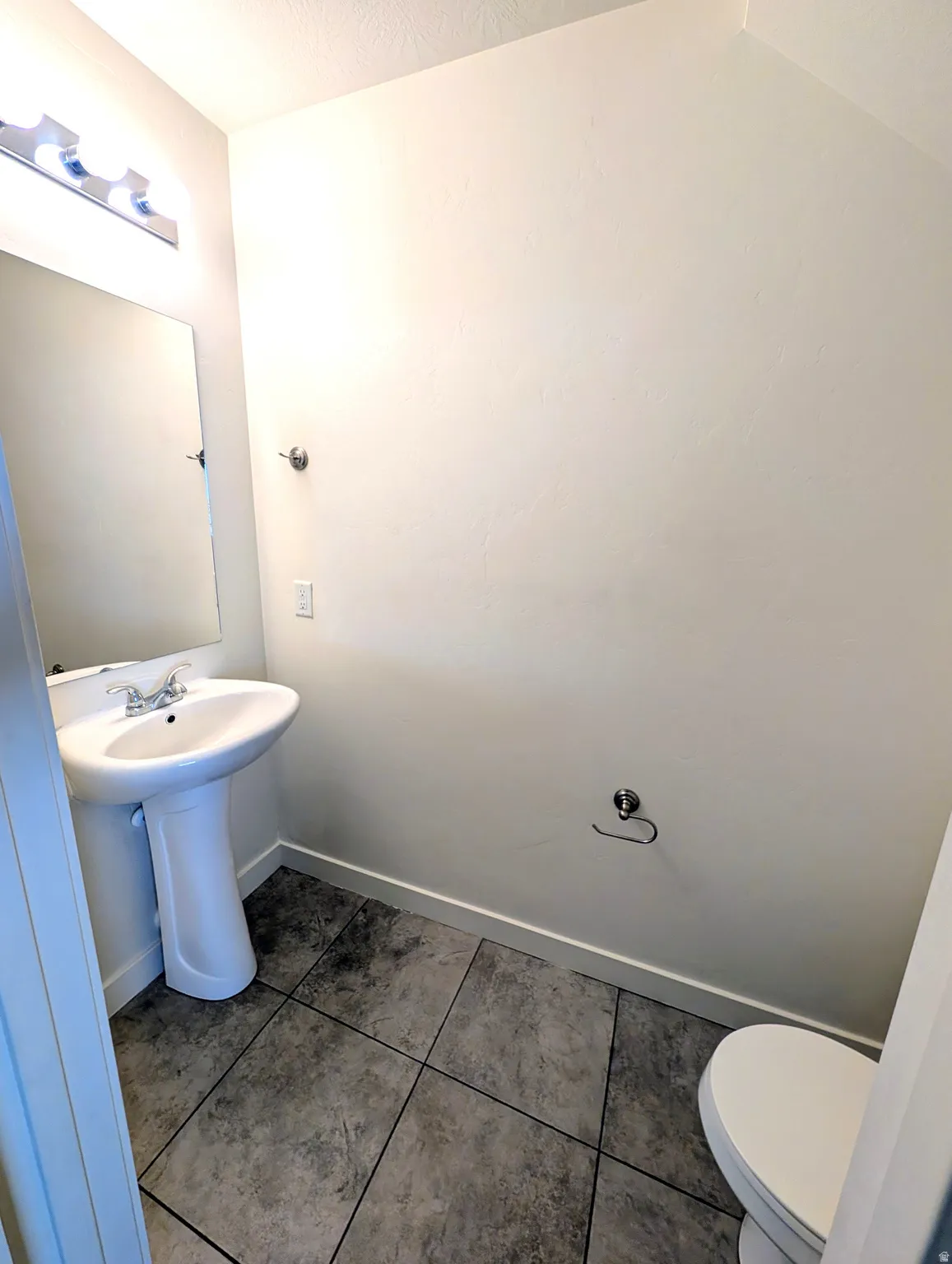 Pedestal sink with a chrome faucet, large vanity mirror, and polished chrome light fixture
