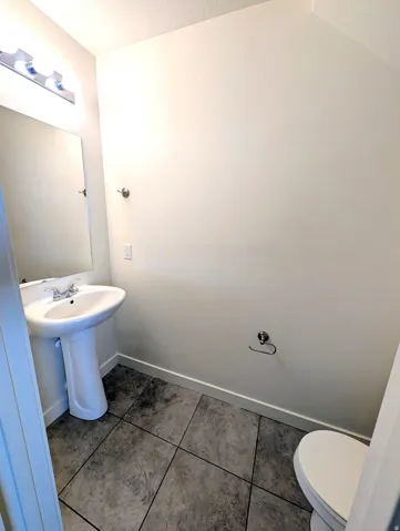 Pedestal sink with a chrome faucet, large vanity mirror, and polished chrome light fixture