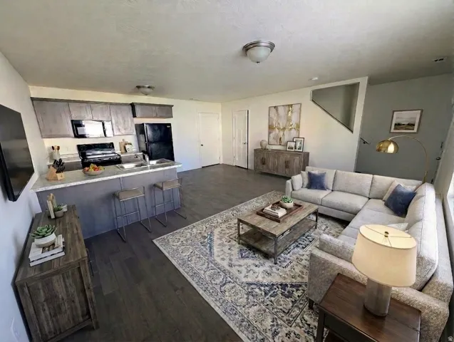 Open concept living area with wood-finish flooring, kitchen island, built-in cabinetry, and integrated staircase