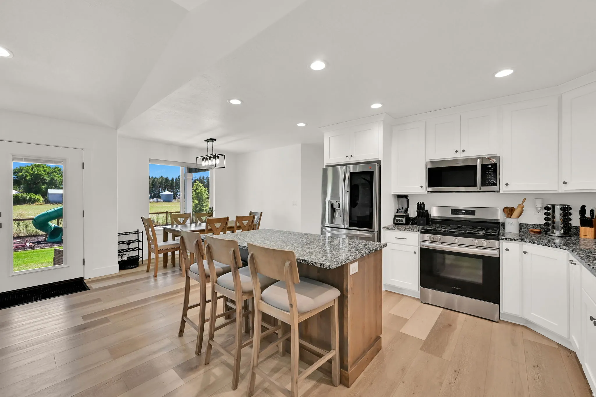 Kitchen featuring white cabinetry, stainless steel appliances, a wood-finish island with a stone-finish countertop, recessed lighting, and wood-finish flooring