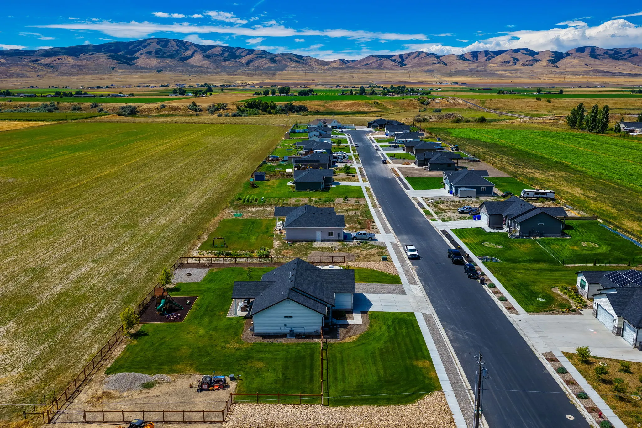 New construction residential development featuring paved streets and sidewalks, with mountain range backdrop