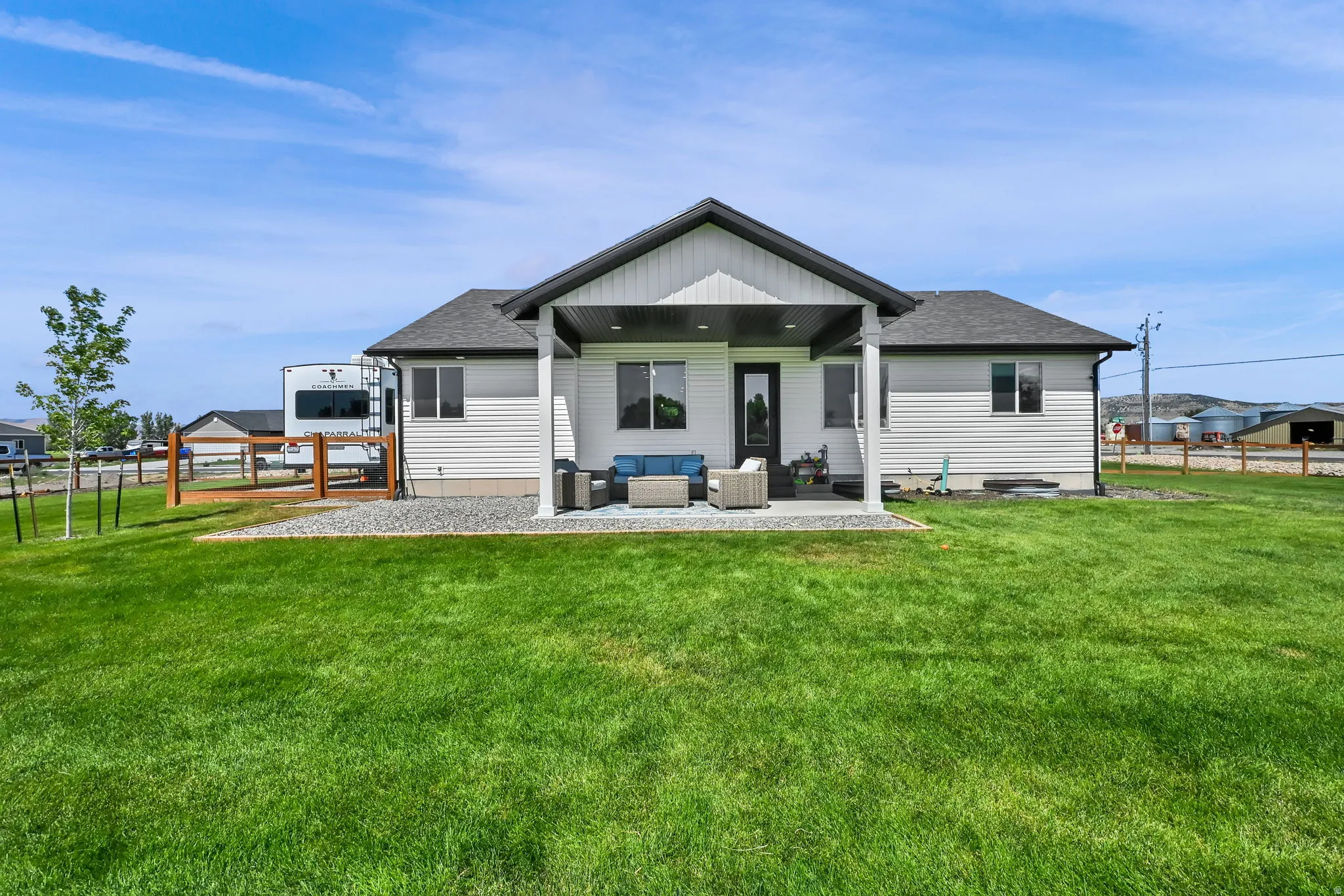 Expansive backyard featuring a covered patio, white siding, and a gravel perimeter