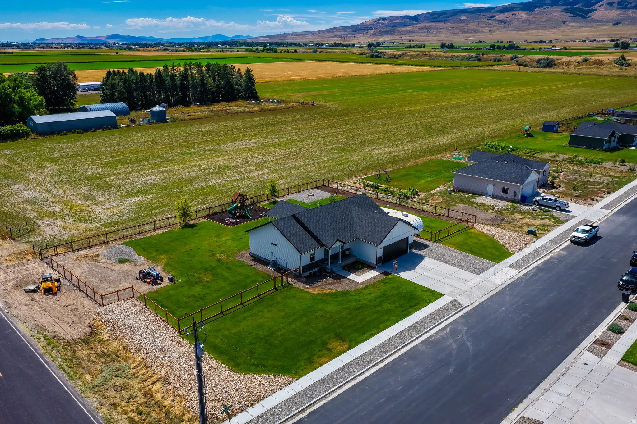 Modern single-story residence with a two-car garage, concrete driveway, and a fenced backyard with a green lawn