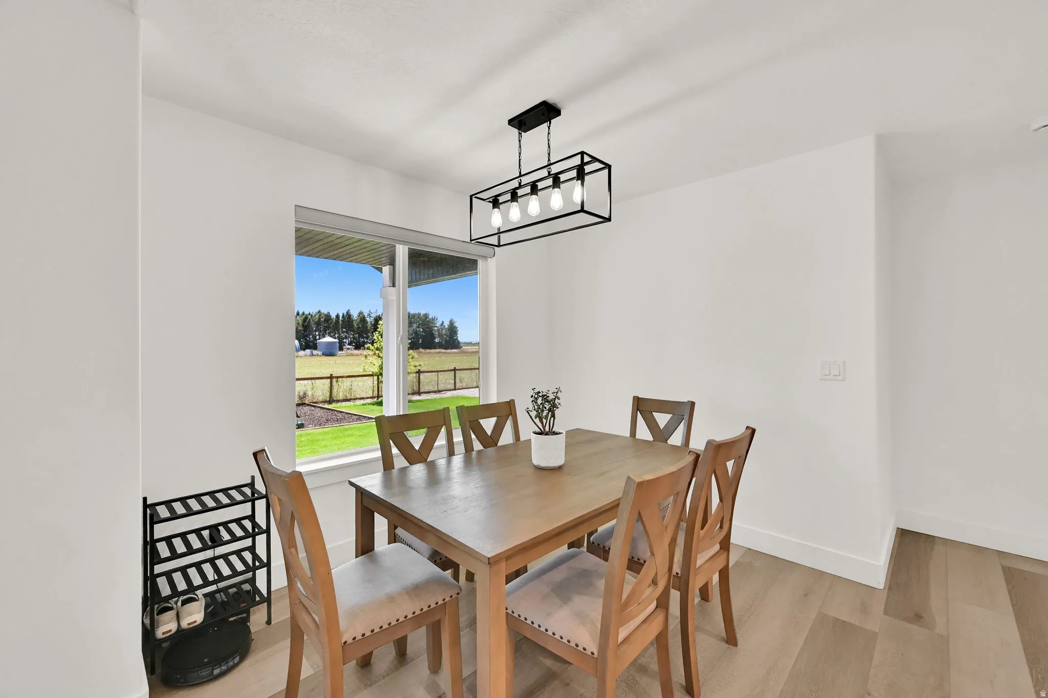 Expansive window, modern linear chandelier, wood-finish flooring, crisp white walls