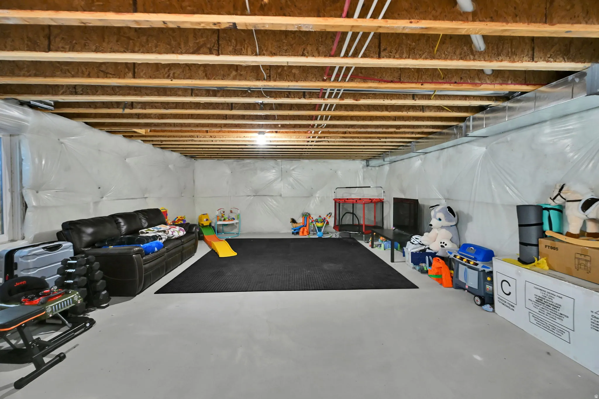 Full unfinished basement with exposed wood joists and concrete flooring