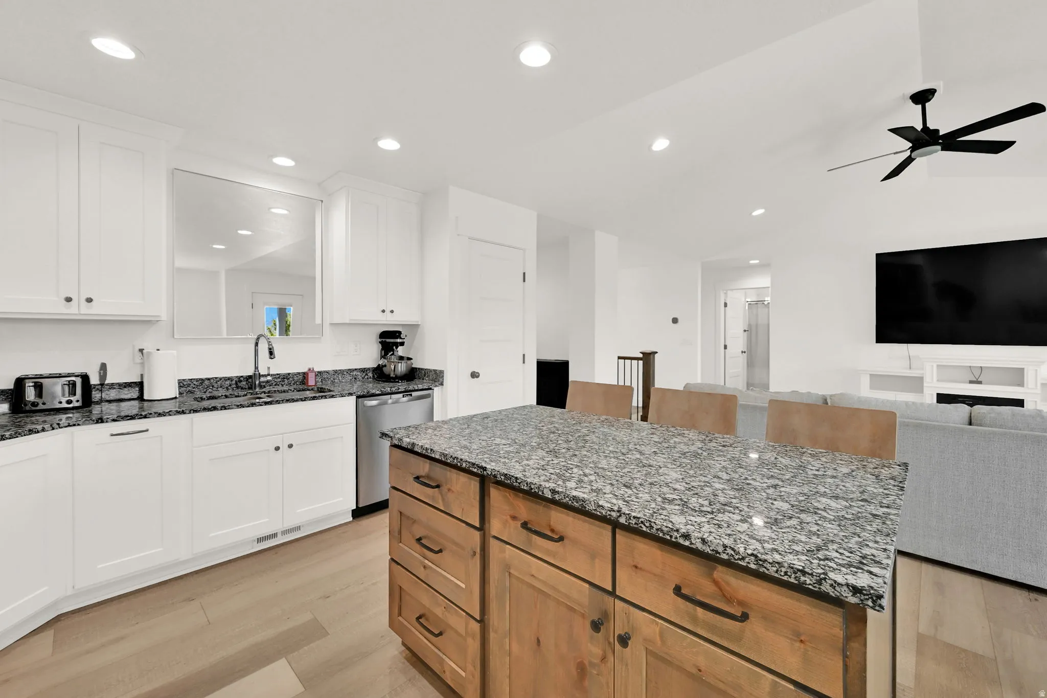 Kitchen featuring white cabinetry, stainless steel dishwasher, wood-finish island with stone countertop, recessed lighting, and wood-finish flooring