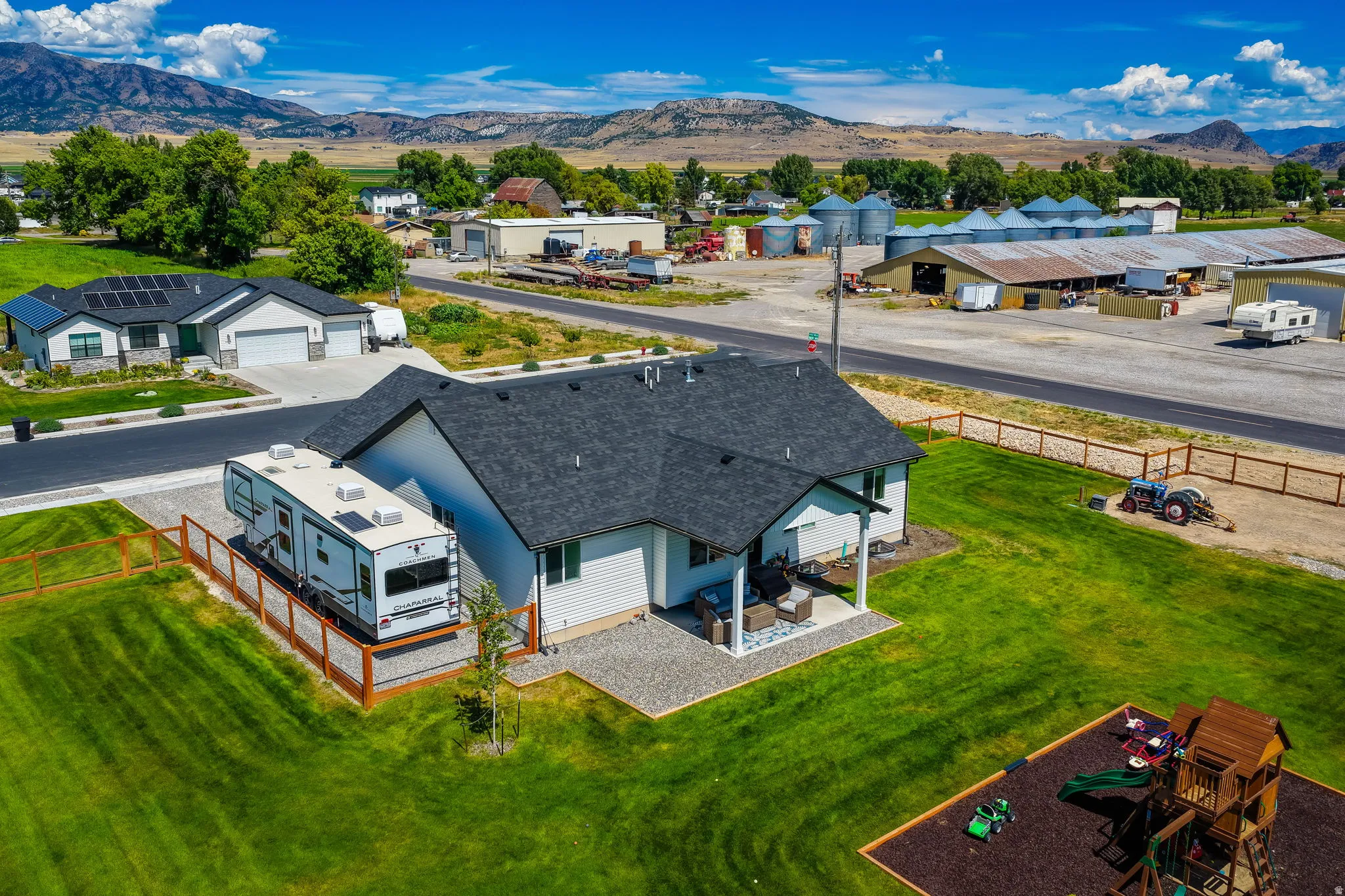 Expansive green lawn, fenced side yard, covered rear patio, and a dedicated gravel pad for recreational vehicle parking
