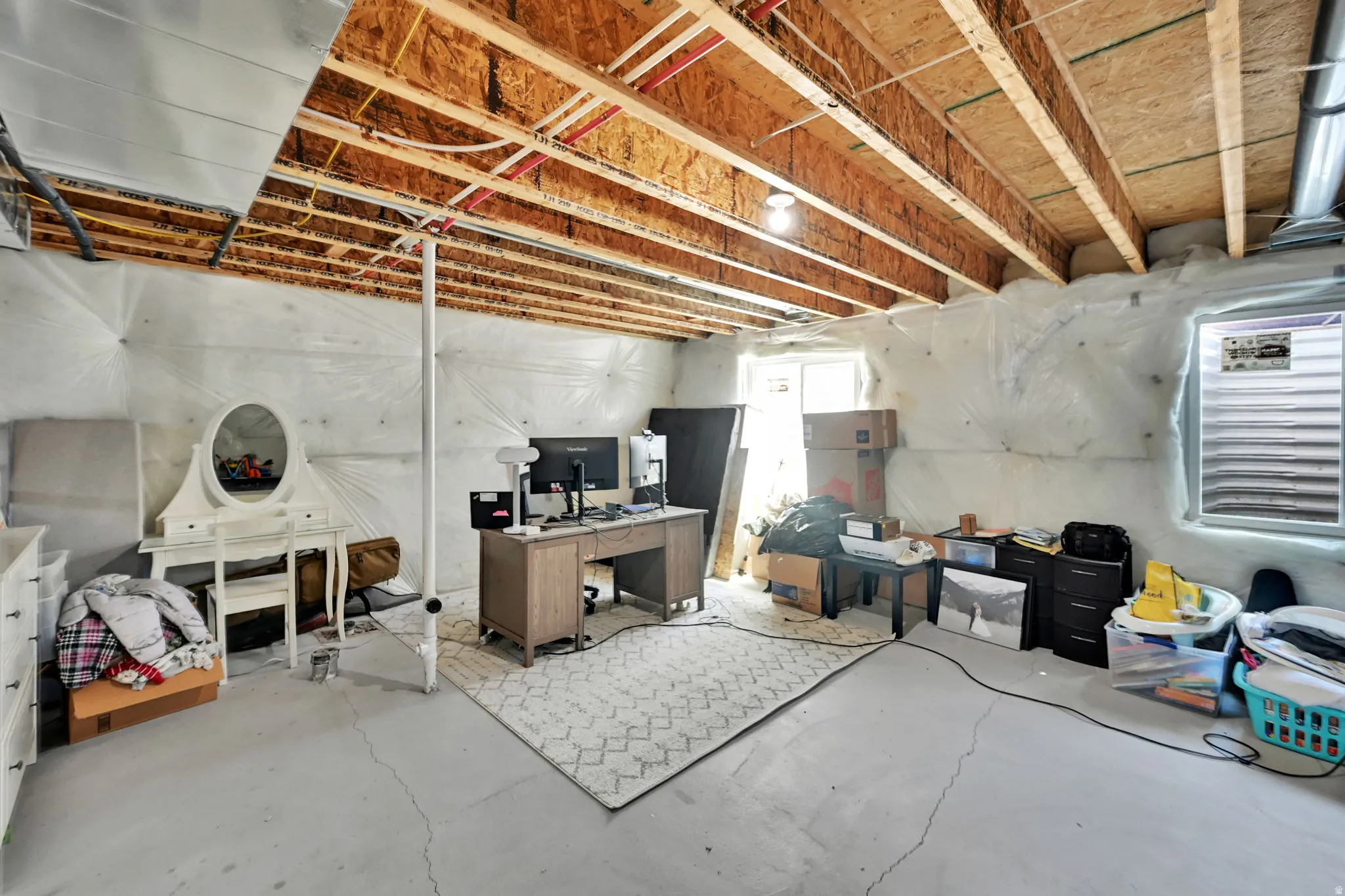 Unfinished basement with exposed ceiling joists and concrete flooring