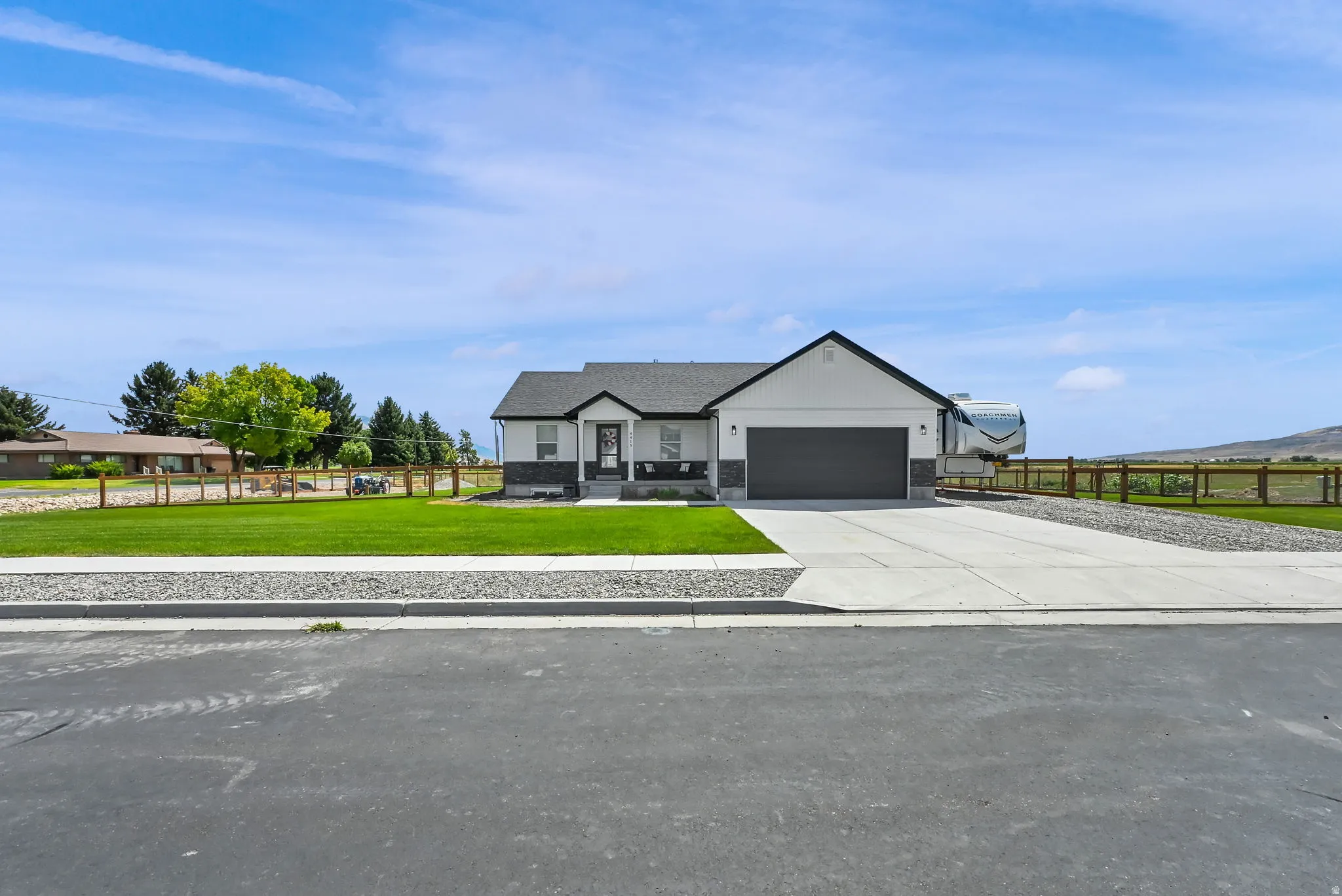Single-story residence featuring a two-car garage, white siding, and stone accents