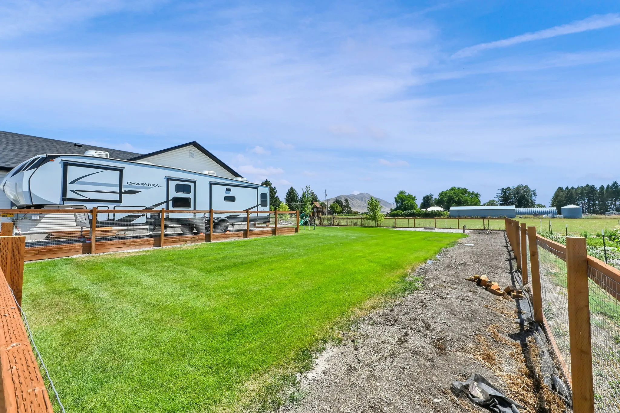 Expansive backyard space with a manicured lawn area and wood-framed wire fencing