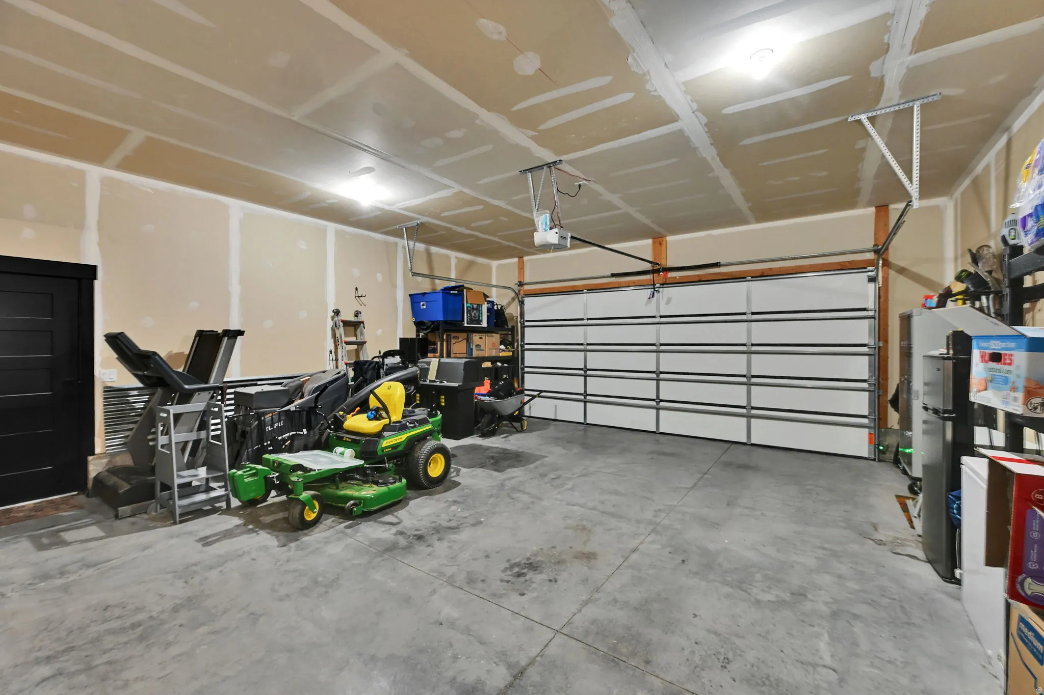 Finished garage with concrete flooring, overhead lighting, and a paneled garage door