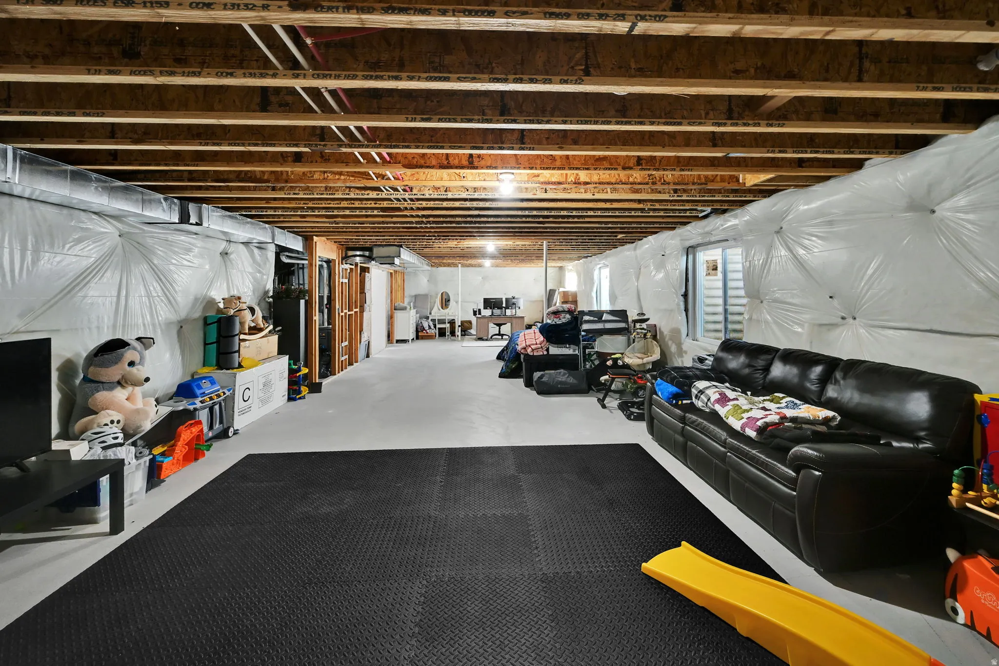 Unfinished basement area with exposed ceiling joists, concrete flooring, and insulated walls