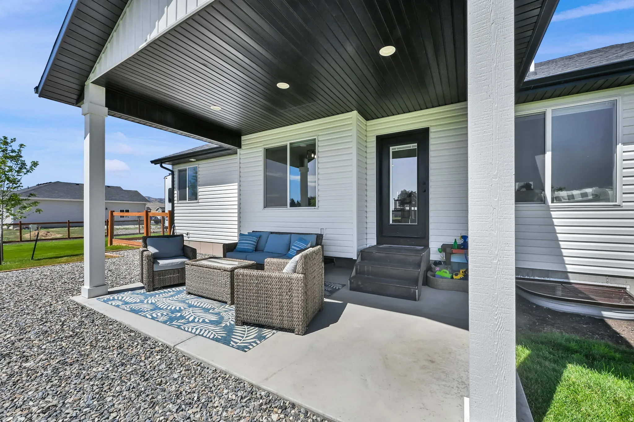 Covered concrete patio with white support columns, recessed lighting, and a black soffit