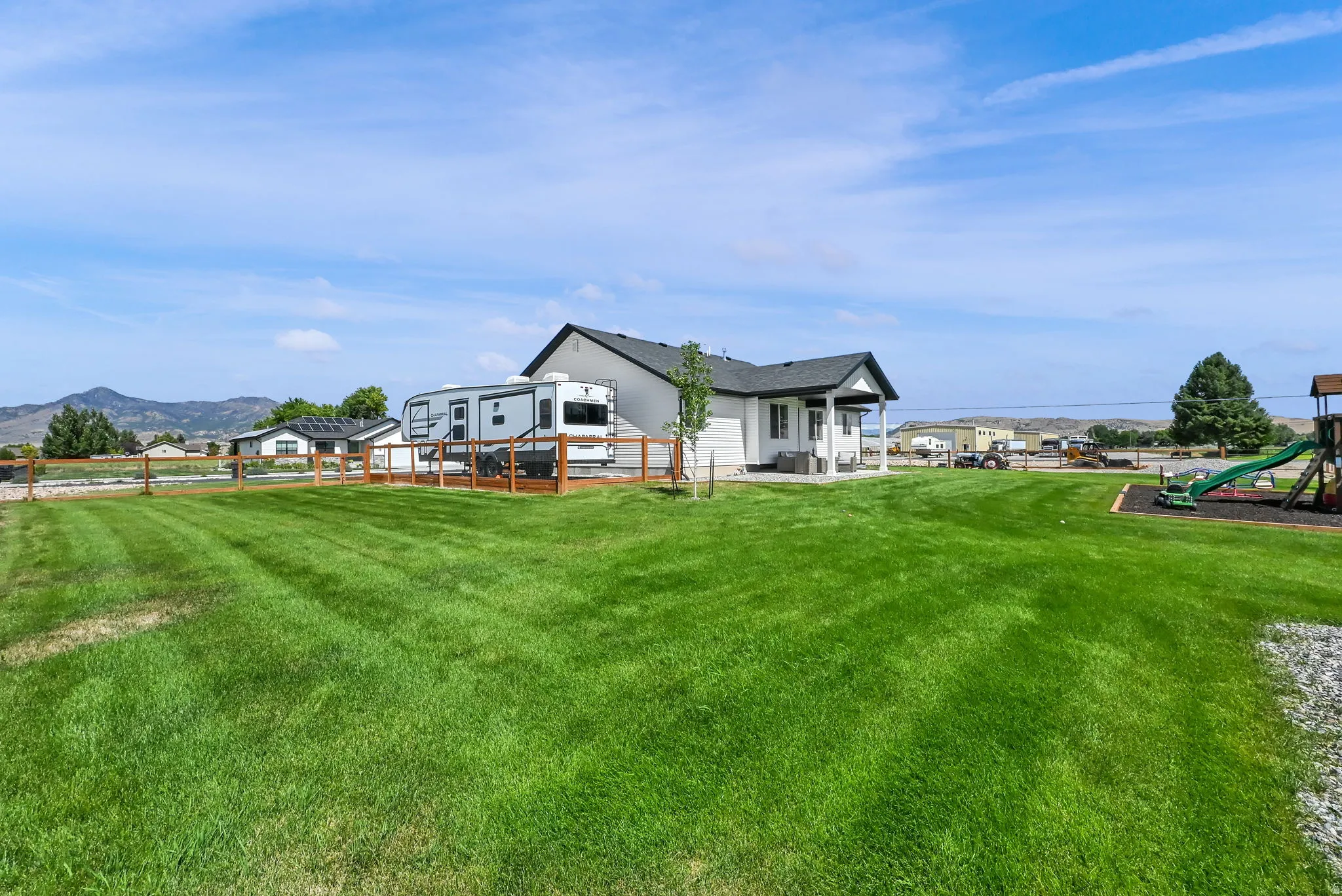 Expansive rear yard featuring a manicured lawn, wood-toned fencing, and a covered back patio