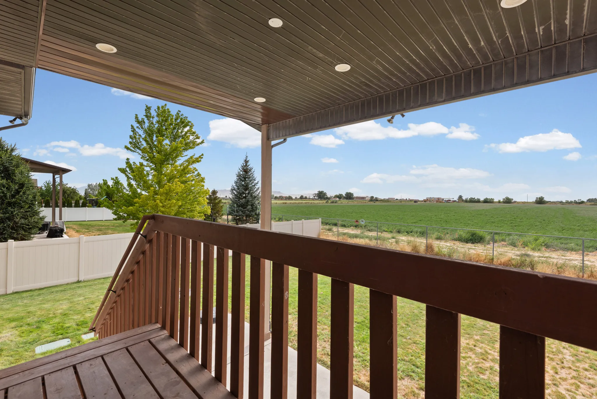 Covered patio featuring recessed lighting, wood-finish decking, and a brown wood railing