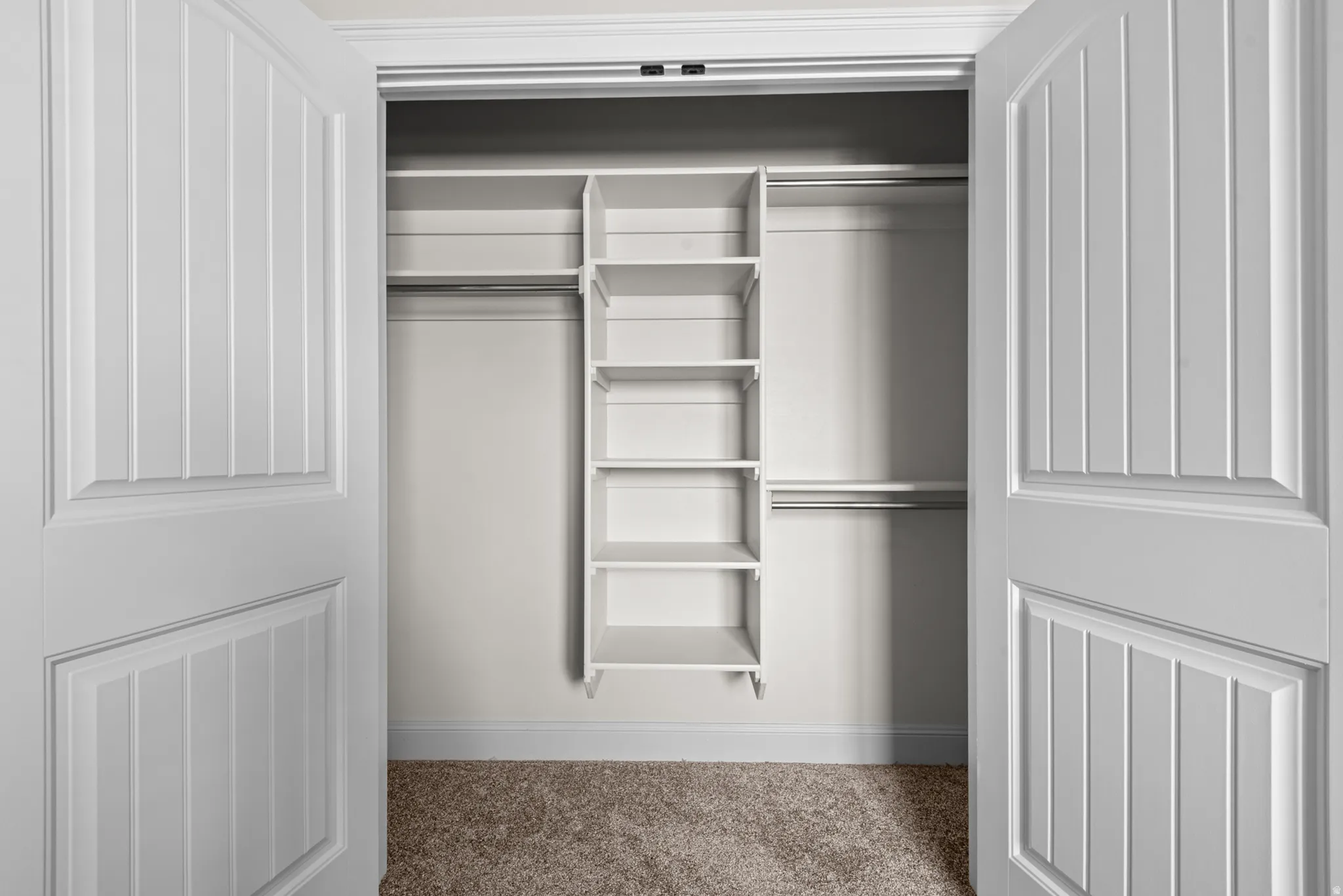 Closet with built-in shelving, dual hanging rods, and paneled doors