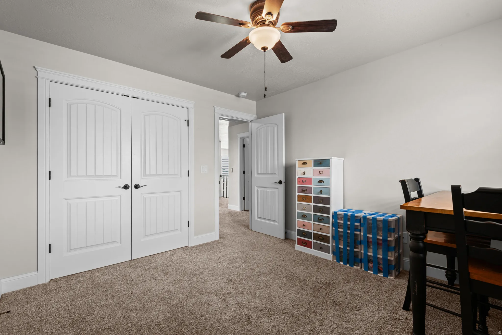 White double doors with black hardware, neutral wall paint, and ceiling fan with integrated lighting