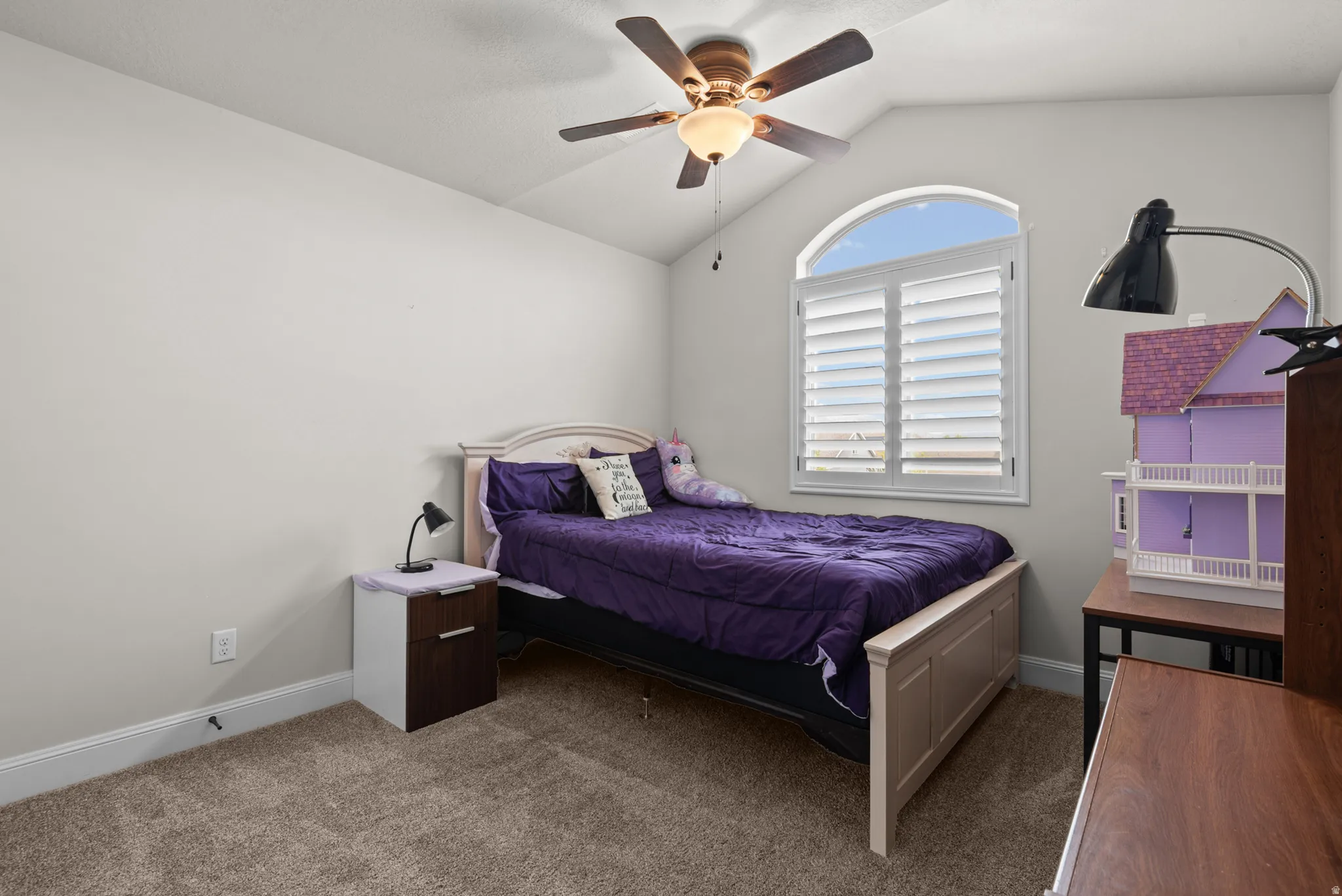 Arched window with plantation shutters, vaulted ceiling, and ceiling fan with integrated lighting