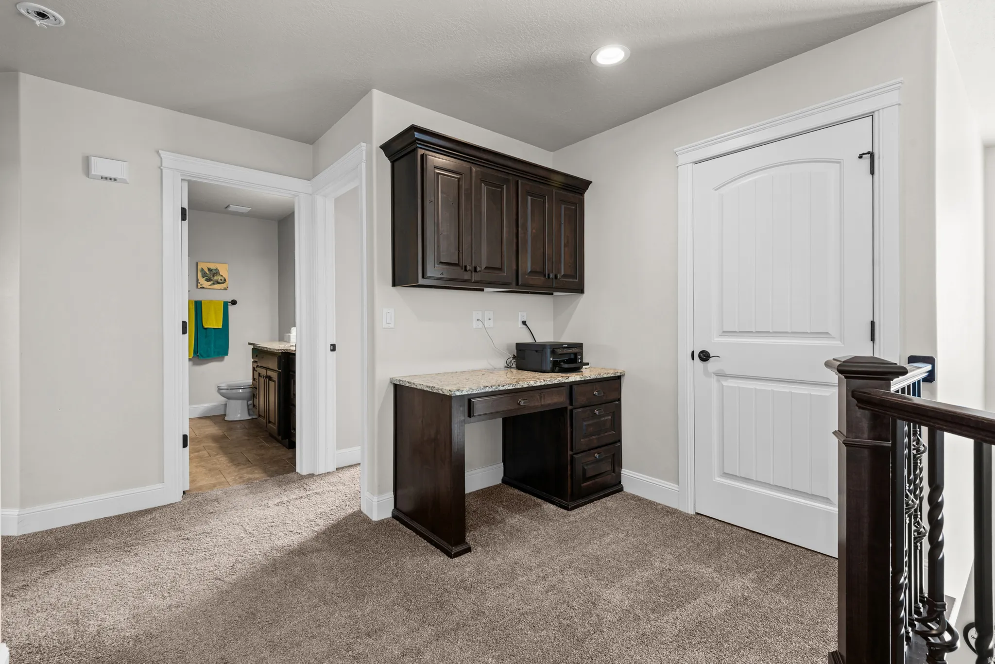 Built-in desk with granite-style countertop, dark wood-finish cabinetry, and recessed lighting