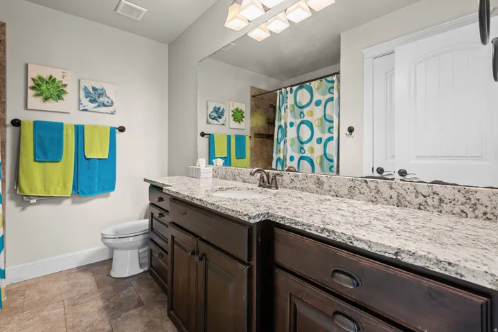 Bathroom featuring a single vanity with dark wood-finish cabinetry, a light-toned countertop, and a large wall-mounted mirror