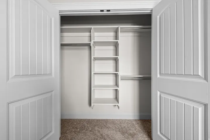 Closet with built-in shelving, dual hanging rods, and paneled doors