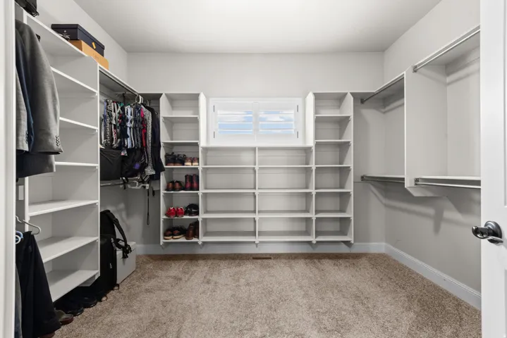 Built-in white shelving, integrated hanging rods, and a window with white shutters