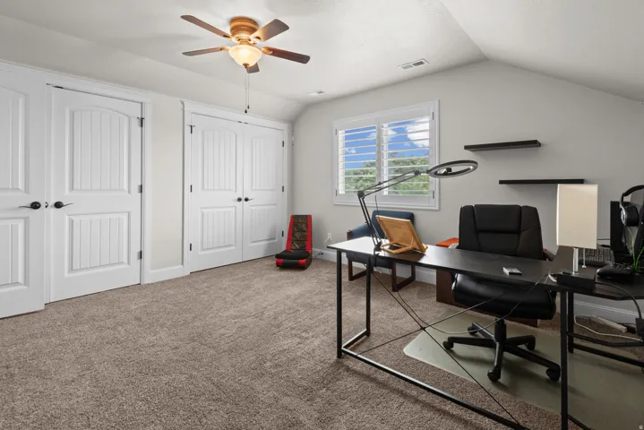 Vaulted ceiling, ceiling fan with integrated lighting, window with plantation shutters, two sets of bi-fold closet doors, and plush carpet flooring