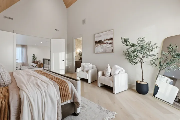 Vaulted ceiling with wood-paneled accent, light wood-finish flooring, and white interior doors with dark hardware