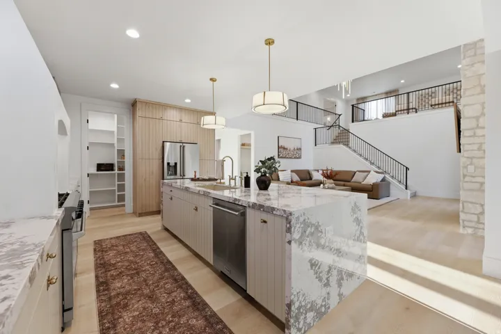 Kitchen island with waterfall countertop, integrated sink, and stainless steel appliances