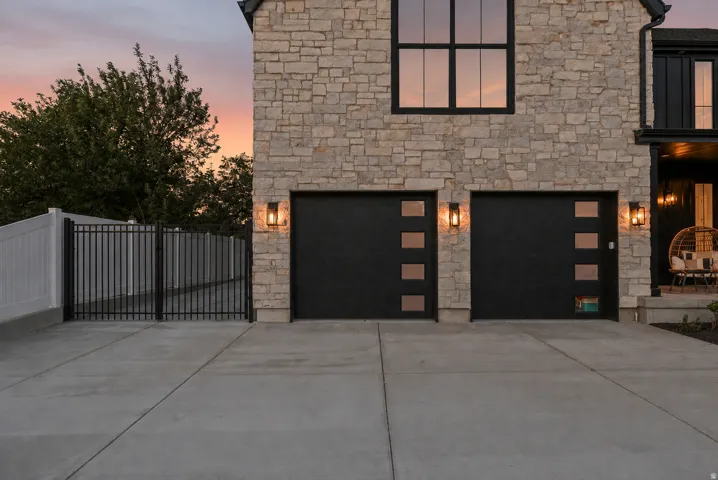 Stone masonry exterior with black-framed windows and two garage doors featuring frosted glass panels