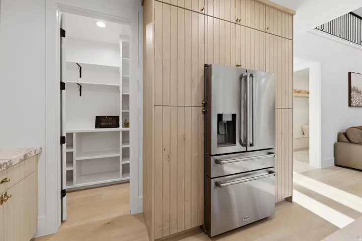 Stainless steel French door refrigerator integrated into custom wood-finish cabinetry