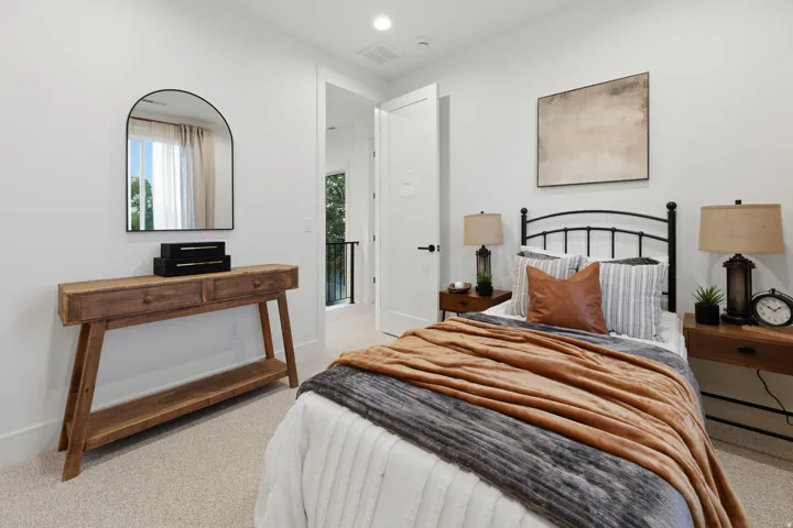 Arched mirror above a wood-finish console table, bright overhead lighting, and a door with matte black hardware
