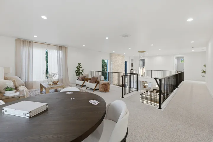 Spacious open-concept upper level featuring neutral carpeting, recessed lighting, and a prominent iron railing