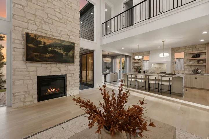 Expansive open-concept living area with a stone-clad fireplace and light wood-finish flooring