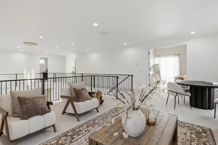 Expansive open-concept living area featuring recessed lighting, a modern chandelier, and black iron railings
