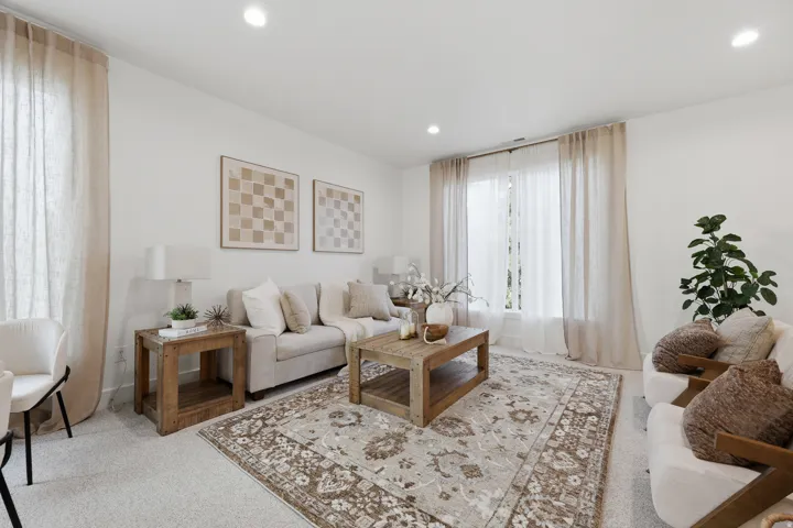 Spacious living area featuring neutral carpeting, recessed lighting, and large windows with ample natural light
