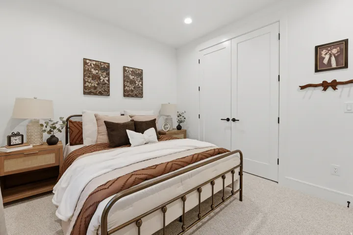 Recessed lighting, light-colored carpeting, two paneled doors with black hardware, and white walls