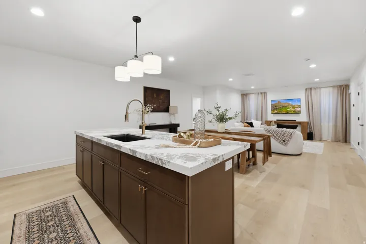 Kitchen island with a dark wood finish and a light-toned countertop, featuring an integrated sink and gooseneck faucet