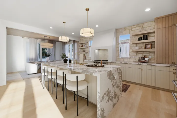 Spacious kitchen featuring a large island with integrated seating, light wood-finish flooring, stone accent wall, open shelving, and a built-in range hood