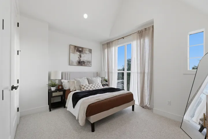 Vaulted ceiling with recessed lighting, large full-height window, additional transom window, and light-toned carpeting