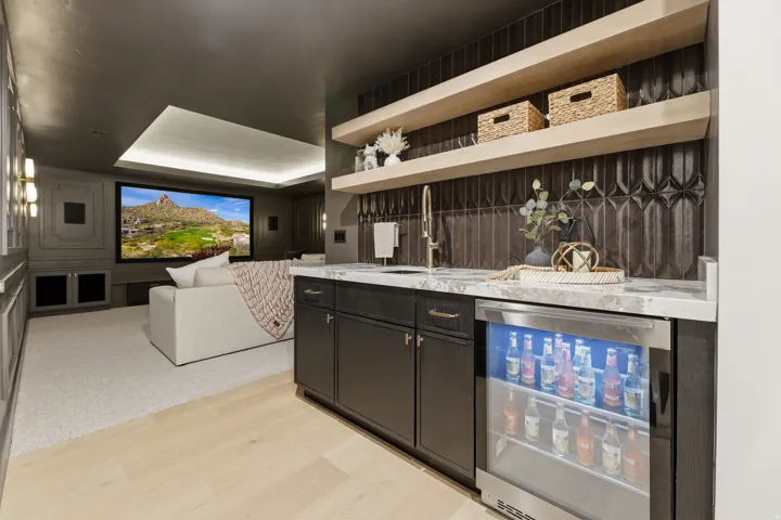 Integrated wet bar with black cabinetry, stone countertop, and beverage refrigerator