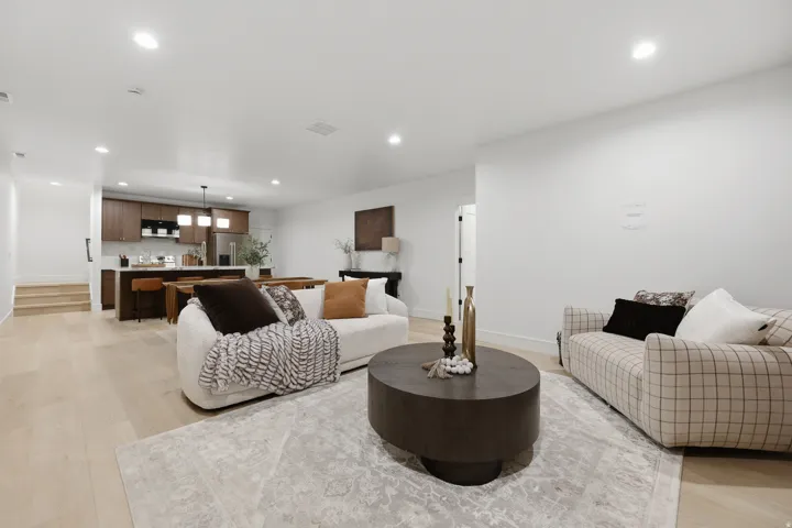 Recessed lighting, wood-finish flooring, white walls, dark wood cabinetry, and a kitchen island with seating